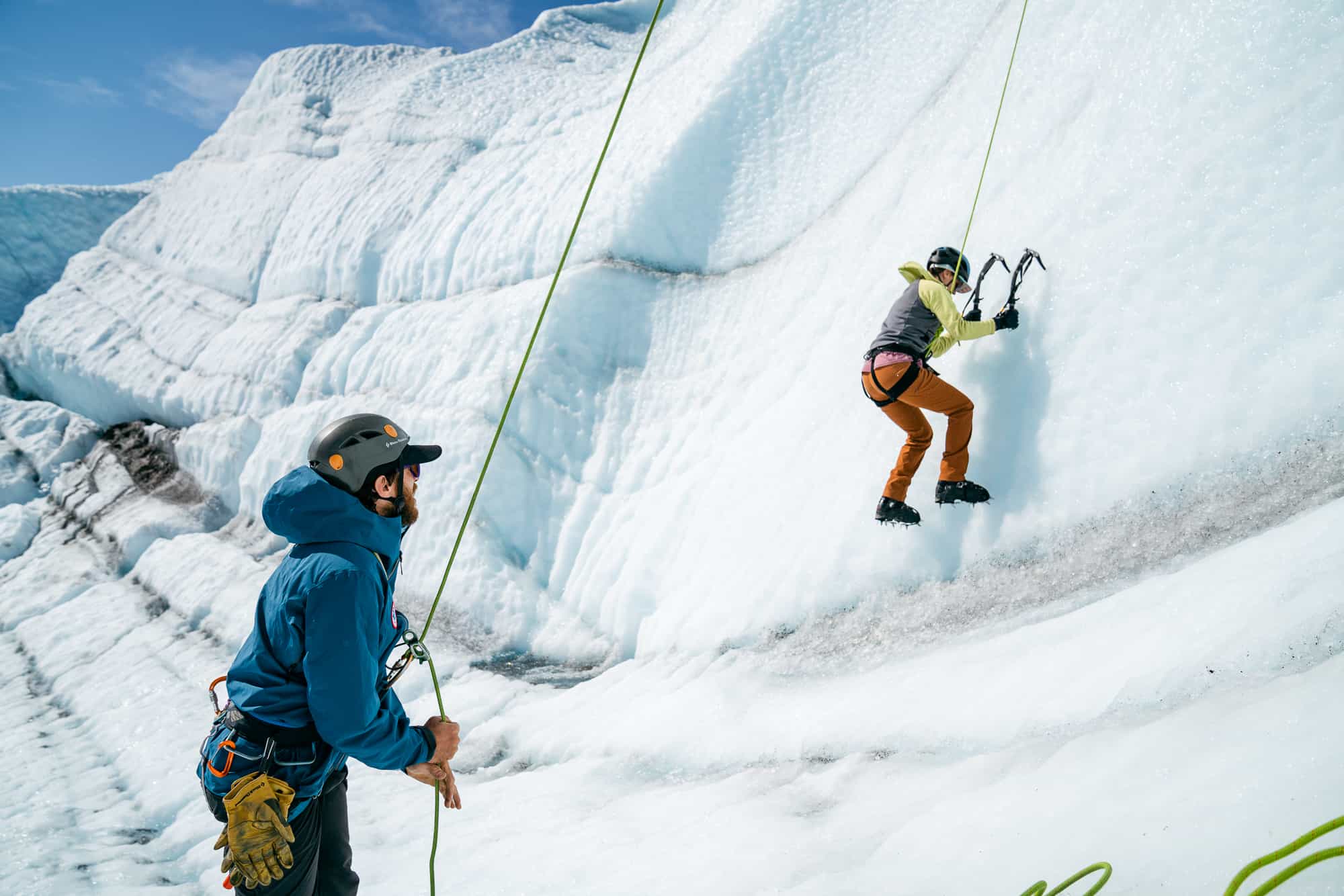 One person belaying another person who is ice climbing